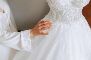 bride touching her wedding dress. High quality photo. A beautiful young bride in a white petticoat is standing by the bed, touching her wedding dress. photo