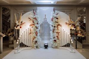 The photo zone at a wedding or birthday celebration is decorated with flowers and illuminated by artificial light