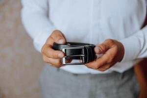 closeup of caucasian man putting on his belt. A stylish man puts on a leather belt close-up. Fashion photo