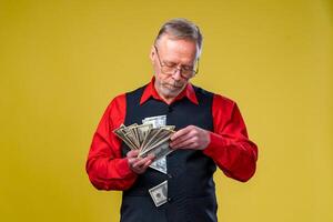 Closeup portrait of super excited senior mature man who just won lots of money, trying to catch or throw dollar bills in air, isolated on white background. Positive emotion facial expression feelings. photo