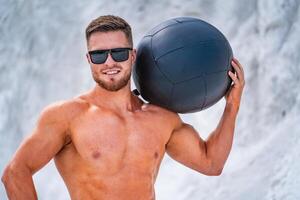 Muscle handsome strong man posing for camera with ball. Bodybuilder portrait. photo