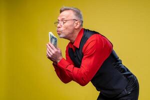 Man holding lots of dollar bills in hands, isolated on yellow background. Happy man enjoying money. Hands with money. Rich with success. Positive emotion facial expression feelings. photo