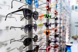 Row of luxury eyeglasses at an opticians store. Sunglasses on the stand. photo