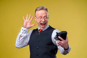 Senior man looking at camera while taking silly face selfie waving to the camera photo