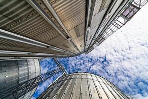 Big cylindrical storage on blue sky. Full length view of the great construction of warehouse. Metallic agricultural building. photo