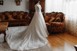 white wedding dress on mannequin in room with german style. Wedding details, modern wedding dress with long train, long sleeves and open back photo