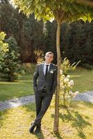 Portrait of a handsome young groom on an autumn day outdoors in an elegant suit. Outdoor photo. Handsome man in a business suit. photo