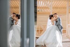 A handsome groom embraces his beloved in a beautiful location. Reflection in the mirror of the bride and groom. Wide format photo. photo