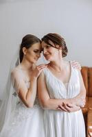 A beautiful and happy mother and her daughter, the bride, are standing next to each other. The best day for parents. Tender moments at the wedding. photo