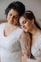 A beautiful and happy mother and her daughter, the bride, are standing next to each other. The best day for parents. Tender moments at the wedding. photo