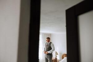 the groom's hands fasten his jacket in the morning before the wedding. close-up of a man in business suit. Businessman puts on a suit. The man fastens the buttons on his jacket. photo