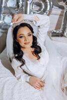 portrait of an incredibly beautiful girl bride in a white robe in the bedroom, the bride poses in the morning before the wedding ceremony. photo