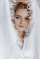 portrait of an incredibly beautiful girl bride in a white robe in the bedroom, the bride poses in the morning before the wedding ceremony. photo