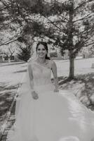 negro y blanco foto. el novia en un Boda vestido, posando con un sincero sonrisa. preparación para el celebracion. hermosa rostro. Boda ceremonia foto