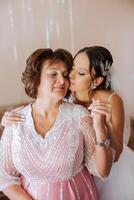 A beautiful and happy mother and her daughter, the bride, are standing next to each other. The best day for parents. Tender moments at the wedding. photo