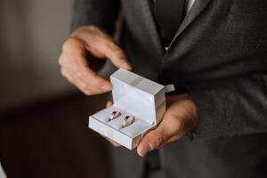 elegante Boda anillos en el manos de el novio. promesas compromiso. lujo matrimonio y Boda accesorio concepto. dos Boda anillos y un Boda invitación. foto