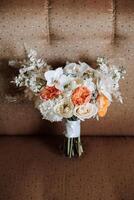 Wedding bouquet. Freshly cut roses, green seed heads and leaves. Green stems, white ribbon and gold wedding rings. The concept of a wedding bouquet. photo