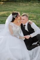 cute and stylish newlyweds are hugging and smiling against the background of autumn nature in a beautiful garden. An incredibly beautiful young bride kisses her lover photo