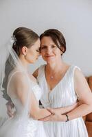 A beautiful and happy mother and her daughter, the bride, are standing next to each other. The best day for parents. Tender moments at the wedding. photo