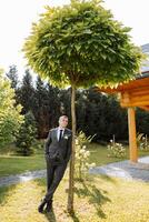 Portrait of a handsome young groom on an autumn day outdoors in an elegant suit. Outdoor photo. Handsome man in a business suit. photo