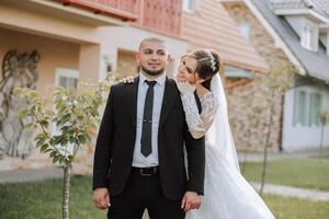 encantador y elegante recién casados son abrazando y sonriente en contra el antecedentes de otoño naturaleza en un hermosa jardín. un increíblemente hermosa joven novia inclinado en contra el hombro de su amado novio foto