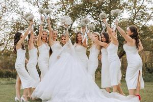 Wedding photography. A brunette bride in a white dress with a bouquet and her brunette girlfriends photo