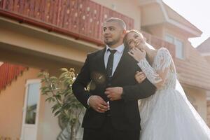 lovely and stylish newlyweds are hugging and smiling against the background of autumn nature in a beautiful garden. An incredibly beautiful young bride leaned against the shoulder of her beloved groom photo