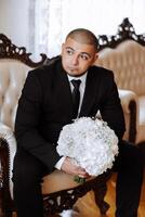 groom with a bouquet of roses, groom with bouquet, groom with a wedding bouquet, a young man with a wedding bouquet on his hand, well suited man photo