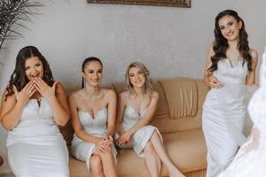 damas de honor alegrarse en el mañana, Ayudar a sujetar el botones en el Boda vestir y preparar para el Boda ceremonia. ellos tomar fotos, sonrisa, ayuda el novia con su zapatos. foto