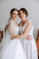 A beautiful and happy mother and her daughter, the bride, are standing next to each other. The best day for parents. Tender moments at the wedding. photo