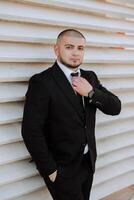 retrato de un hermoso joven novio en un otoño día al aire libre en un elegante traje. al aire libre foto. hermoso hombre en un negocio traje. foto