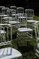 Decor at the wedding. Transparent chairs on green grass. photo