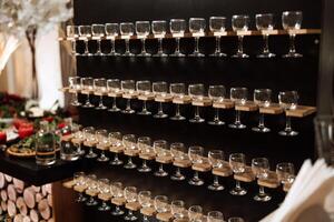 Champagne glass stand at a wedding party. Glasses for alcoholic drinks on a black wooden stand. Alcohol. Champagne. Celebration. photo