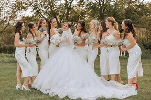 Wedding photography. A brunette bride in a white dress with a bouquet and her brunette girlfriends photo