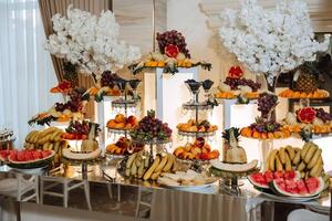 A banquet table full of fruits and berries, an assortment of sweets. Bananas, grapes, pineapples. Fruit compositions for the holiday. photo