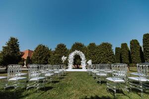 Decor at the wedding. Many transparent chairs on the green grass. photo