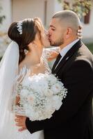 A young bride and groom tenderly embrace in the rays of the autumn sun. Tender and beautiful young girl bride. A man kisses his beloved. Against the background of a beautiful garden photo