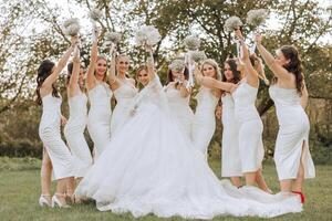 Wedding photography. A brunette bride in a white dress with a bouquet and her brunette girlfriends photo