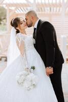 A young bride and groom tenderly embrace in the rays of the autumn sun. Tender and beautiful young girl bride. A man kisses his beloved. Against the background of a beautiful garden photo