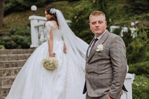 A wedding couple is walking in nature on an autumn day. Happy young bride and elegant groom holding hands. A stylish couple of newlyweds on their wedding day. photo