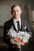 groom with a bouquet of roses, groom with bouquet, groom with a wedding bouquet, a young man with a wedding bouquet on his hand, well suited man photo