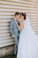 A young bride and groom tenderly embrace in the rays of the autumn sun. Tender and beautiful young girl bride. A man kisses his beloved. Against the background of a beautiful garden photo