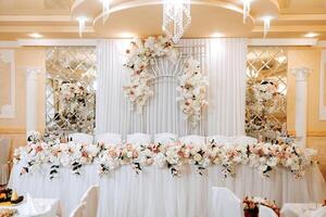 table setting in a restaurant for a holiday. Wedding decor for the newlyweds at the banquet. Floristry of fresh flowers and candles, boho style. Catering for the bride and guests. photo