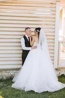 A young bride and groom tenderly embrace in the rays of the autumn sun. Tender and beautiful young girl bride. A man kisses his beloved. Against the background of a beautiful garden photo