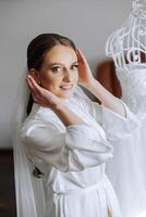 Morning preparation of an incredibly beautiful bride. A girl in a beautiful robe near a wedding dress standing on a mannequin indoors. Wedding preparations of the bride. photo