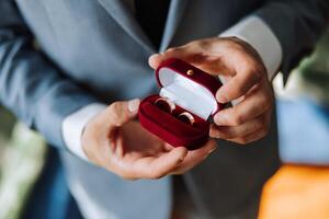 el joven novio sostiene Boda anillos en su mano. el hombre sostiene dos oro Boda anillos en su mano. Boda ceremonia. foto