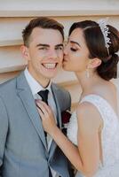 cute and stylish newlyweds are hugging and smiling against the background of autumn nature in a beautiful garden. An incredibly beautiful young bride kisses her lover photo