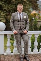 Portrait of a handsome young groom on an autumn day outdoors in an elegant suit. Outdoor photo. Handsome man in a business suit. photo