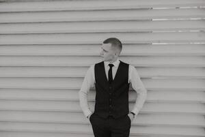 Portrait of a handsome young groom on an autumn day outdoors in an elegant suit. Outdoor photo. Handsome man in a business suit. photo