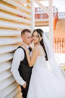 A young bride and groom tenderly embrace in the rays of the autumn sun. Tender and beautiful young girl bride. A man kisses his beloved. Against the background of a beautiful garden photo